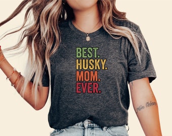 May include: A dark grey t-shirt with the text "BEST. HUSKY. MOM. EVER." printed in colorful retro-style lettering.