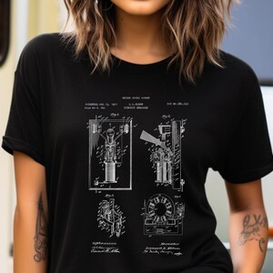 Puede incluir: Una camiseta negra de manga corta con un estampado gráfico blanco de una patente estadounidense para un disyuntor de L.L. Elder. El diseño incluye diagramas técnicos etiquetados como Fig 1, Fig 2, Fig 3 y Fig 4, junto con el texto de la patente.