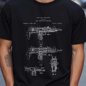 May include: A black t-shirt with a white print of a UZI GAL semi-automatic firearm patent drawing. The patent drawing includes four different views of the firearm, labeled "FIG 1", "FIG 3", "FIG 8", and "FIG 4". The patent was filed on June 22, 1982, and the patent number is 4,336,643.