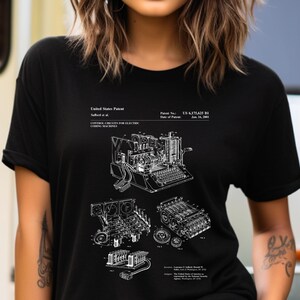 May include: A black t-shirt featuring a white graphic print of a United States Patent for control circuits for electric coding machines. The design includes technical line drawings of the machinery, patent number US 6,175,625 B1, and text.