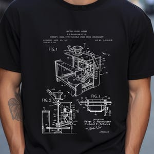 May include: Black t-shirt featuring a white schematic diagram of a potter's wheel with variable speed drive arrangement. The diagram includes labels and figures, with text indicating the patent information and inventors' names.