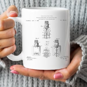 May include: White ceramic mug with a black and white illustration of a patent for an automatic fire sprinkler. The patent is dated September 4, 1888 and is titled "Automatic Fire-Sprinkler". The patent number is 388,905.