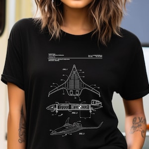 以下が含まれることがあります： 商用航空機の特許図面の白いグラフィックプリントが施された黒いTシャツ。デザインには、Fig. 1、Fig. 2、Fig. 3とラベル付けされた3つの技術的図面と、特許出願公開に関する詳細なテキストが含まれています。