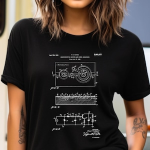 May include: A black t-shirt featuring a white graphic print of a technical patent illustration for a semiconductor device and lead structure. The design includes detailed schematics, labeled figures, and text reading April 25, 1961, R.N. Noyce, 2,981,877.