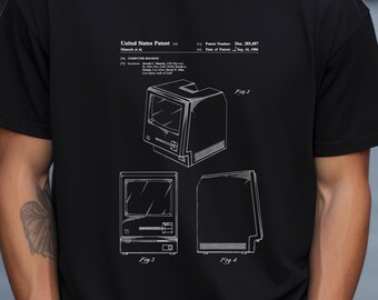 Puede incluir: Una camiseta negra con un estampado gráfico blanco de una patente estadounidense para una carcasa de ordenador, número de patente Des. 285,687, con fecha del 16 de septiembre de 1986. El diseño incluye tres dibujos técnicos de líneas etiquetados Fig. 1, Fig. 2 y Fig. 4.