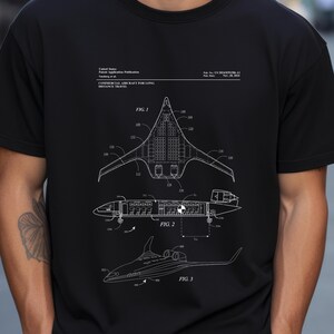 May include: A black t-shirt featuring a white technical patent illustration of a commercial aircraft for long distance travel. The graphic includes three distinct views labeled Fig. 1, Fig. 2, and Fig. 3, along with detailed schematics and text.