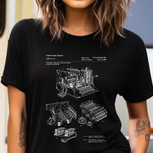 May include: A black short-sleeved t-shirt featuring a white graphic print of a United States Patent for control circuits for electric coding machines. The design includes technical line drawings, patent number 6,175,625 B1, and date January 16, 2001.