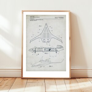 May include: Framed print of a vintage aircraft patent. The diagram shows three views of a commercial aircraft for long-distance travel. The print features detailed technical drawings with labels and measurements, set against a neutral background.