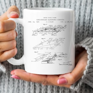 May include: A white ceramic mug with a black and white image of a patent for a miniaturized electronic circuit. The patent is titled "Miniaturized Electronic Circuits" and was filed by J.S. Kilby on June 23, 1964. The patent number is 3,138,743.