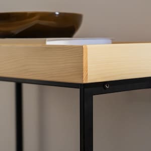 Pu&ograve; includere: Uno scaffale in legno con una struttura in metallo nero. Lo scaffale &egrave; in legno chiaro e ha una finitura naturale. La struttura in metallo &egrave; nera e ha un design semplice.