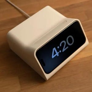 May include: A white charging dock with a black screen displaying the time 4:20.
