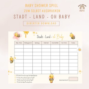Könnte beinhalten: Ein druckbares Baby Shower Spiel auf Deutsch, genannt "Stadt - Land - Oh Baby". Das Spiel ist eine Variation des klassischen "Städte, Länder, Hauptstädte" Spiels. Das Spielbrett hat Spalten für Babynamen, Kleidungsstücke, Spielzeug, Kinderlieder, Einschlafrituale und das erste Wort, das das Baby gesagt hat. Spieler erhalten Punkte für einzigartige Antworten. Das Spiel ist mit einem niedlichen Bienen- und Blumendesign verziert.