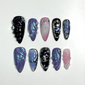 Könnte beinhalten: Set mit zehn falschen Nägeln mit verschiedenen Designs. Die Nägel sind in verschiedenen Farben, darunter Schwarz, Blau, Rosa und Lila. Einige Nägel haben Wirbel, Glitzer und Strasssteine.