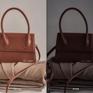 May include: A brown leather handbag with a structured design, featuring a top handle and a shoulder strap. The bag is placed on top of folded clothing. The brand name "JACQUEMUS" is visible on the front.
