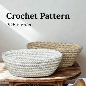 Peut inclure: Deux paniers crochetés, un blanc et un beige, sont posés sur un tabouret en bois rustique. Le texte "Crochet Pattern PDF + Video" est affiché. Du blé et du pain sont disposés à proximité, suggérant un thème de décoration ou d'artisanat.