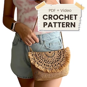 Pode incluir: Uma bolsa transversal de ráfia tecida com uma aba decorativa de crochê e franjas. A bolsa tem uma alça longa e fina. O texto na imagem diz "PDF + Video CROCHET PATTERN."