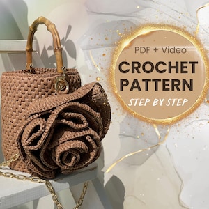 Könnte beinhalten: Eine braune gehäkelte Handtasche mit einem Bambusgriff und einer großen gehäkelten Blume. Die Tasche hat einen goldenen Kettenriemen. Das Bild enthält den Text "PDF + Video CROCHET PATTERN STEP BY STEP".