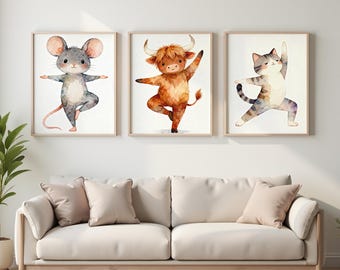 May include: Three framed watercolor prints featuring animal yoga poses. A gray mouse, a brown Highland cow, and a gray and white cat are depicted in various yoga poses. The prints are displayed above a cream-colored sofa with matching pillows.