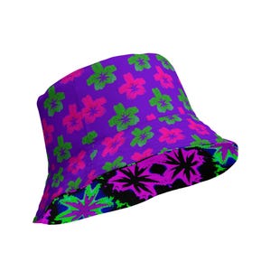 May include: A reversible bucket hat featuring a purple base with a repeating pattern of bright pink and lime green flowers on one side, and a black base with a vibrant neon pink and green starburst or floral pattern on the underside brim.