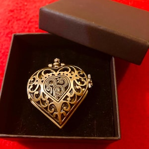 Elegant metalen hartvormig zakhorloge met een uitgesneden deksel. Verkrijgbaar in goud of zwart.