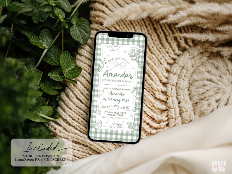 May include: A smartphone displays a mobile invitation for Amanda's 1st Farmers Market and birthday celebration. The invitation features a green and white gingham pattern, with text and illustrations of vegetables and fruits. The background includes greenery and a beige knitted texture.