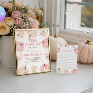 May include: A framed "Time Capsule" sign and a matching card, both decorated with pink pumpkins and floral accents. The sign is for Melania's 18th birthday. A bouquet of roses and pumpkins are in the background.