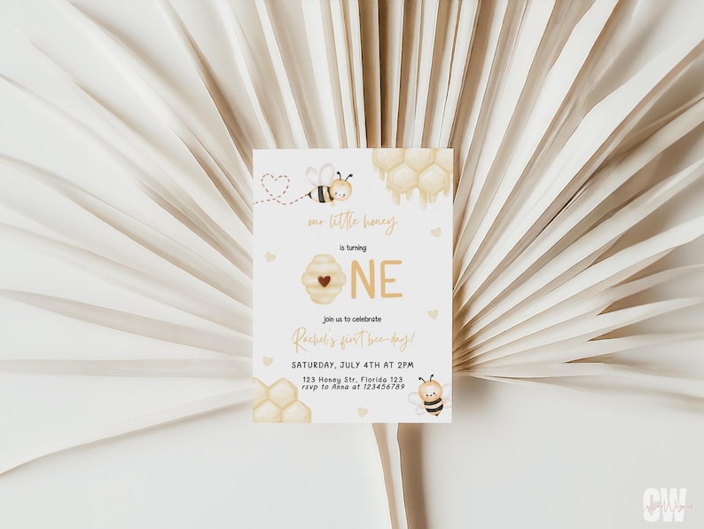 Op de afbeelding: Een witte uitnodigingskaart met een bij- en honingraatontwerp. De tekst op de kaart luidt "Mr. Little Honey wordt EEN. Vier met ons Rachels eerste bijendag! Zaterdag 4 juli om 14:00 uur. 123 Honey St, Florida 123. RSVP naar [telefoonnummer]"