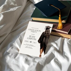 May include: White graduation party invitation with black text. The invitation says "Please join us for a Graduation Party honoring Ruby Griffin Saturday, June 16 The Fulton Residence 88 Park Ave, Santa Barbara, CA RSVP by June 10 to Rachel 123-456-7890". The invitation features a black and white illustration of a person wearing a graduation cap and gown.