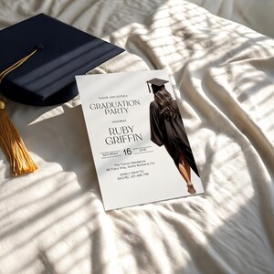 May include: White graduation party invitation with black text. The invitation features a black and white photo of a graduate wearing a cap and gown. The text reads "Please join us for a Graduation Party honoring Ruby Griffin Saturday June 16 The Falcon Residence 66 Ferry Way, Santa Barbara, CA Kindly RSVP to Rachel 123-456-789".