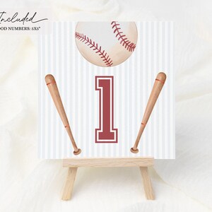 Peut inclure: Une conception sur le th&egrave;me du baseball avec une balle, deux battes et le chiffre 1 en bordeaux. Le fond pr&eacute;sente des rayures verticales. Les mots "Included" et "6 FOOD NUMBERS: 5X5" sont dans le coin sup&eacute;rieur gauche. Le design est affich&eacute; sur un petit chevalet en bois.