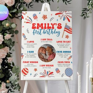 Puede incluir: Un letrero blanco sobre un caballete, que celebra un primer cumpleaños. El letrero presenta el texto "Emily's first birthday" en rojo y azul, junto con una foto y detalles como la altura (73,66 cm) y el peso (9,07 kg).