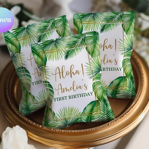 May include: Three party favor bags with a tropical leaf design and gold text that reads "Aloha! Amelia's FIRST BIRTHDAY". The bags are arranged on a gold-colored tray.