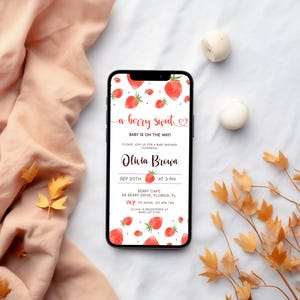 Puede incluir: Un tel&eacute;fono inteligente que muestra una invitaci&oacute;n a una fiesta de bienvenida al beb&eacute; con un tema de fresa. La invitaci&oacute;n dice "a berry sweet" e incluye el texto "Baby is on the way!" La invitaci&oacute;n es para Olivia Brown y est&aacute; programada para el 20 de septiembre a las 3 PM en Berry Cafe.