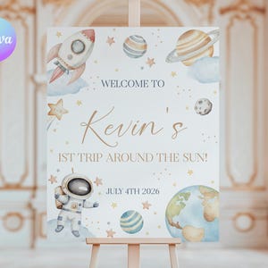 Puede incluir: Un cartel de bienvenida blanco con un tema espacial azul y dorado. Dice "Welcome to Kevin's 1st Trip Around the Sun!" y "July 4th 2026". Hay ilustraciones de un cohete, planetas, estrellas y un astronauta.