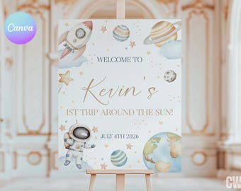May include: A white welcome sign with a blue and gold space theme. It says "Welcome to Kevin's 1st Trip Around the Sun!" and "July 4th 2026". There are illustrations of a rocket, planets, stars, and an astronaut.
