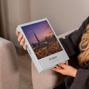 May include: A rectangular light grey decorative book box featuring a high-resolution photograph of the Dubai skyline at sunset, including the Burj Khalifa and highway interchanges. The text DUBAI UAE 25.0113 N 55.0093 E is printed on the front.