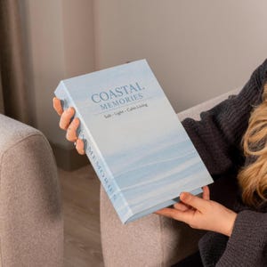 以下が含まれることがあります： COASTAL MEMORIESおよびSalt · Light · Calm Livingというテキストが記載された、水彩画風のライトブルーの表紙を持つ長方形の本。背表紙にも青い背景に縦書きでCOASTAL MEMORIESというテキストが記載されている。