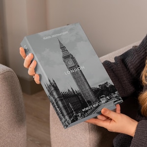 May include: A gray book with a black and white image of the London skyline, including Big Ben and the Houses of Parliament. The book has the words "TRAVEL DESTINATIONS", "LONDON", and "WORLD'S BEST CITIES" printed on it.