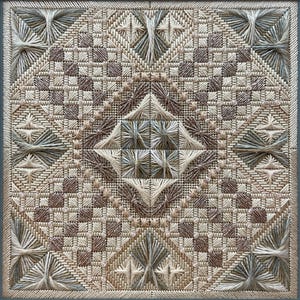 Op de afbeelding: Vierkant, handgestikt textielkunstwerk met een geometrisch ontwerp. Het stuk heeft een herhalend patroon van vierkanten, ruiten en sterren in tinten beige, bruin en grijs. De textuur is ingewikkeld, met zichtbaar draadwerk.