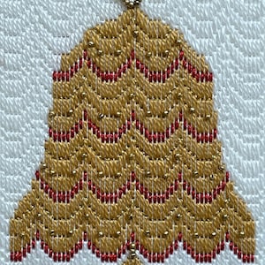 May include: A handcrafted bell-shaped ornament with a gold and red beaded design. The ornament features a scalloped edge and a small loop at the top for hanging. The background is a white, textured fabric.