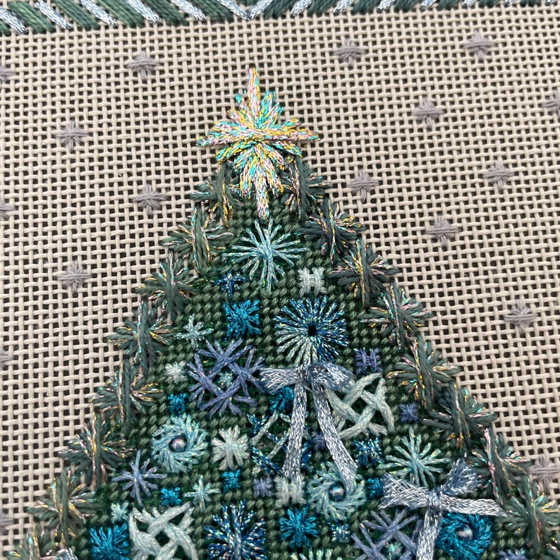 Peut inclure: Gros plan d'un sapin de No&euml;l brod&eacute; en vert et bleu avec une &eacute;toile scintillante au sommet. L'arbre est d&eacute;cor&eacute; de n&oelig;uds et de perles.