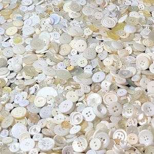 May include: A large collection of white buttons of various sizes and shapes. The buttons are made of a smooth, pearly material.