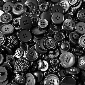 May include: A collection of various black and gray buttons of different sizes and styles. The buttons have two or four holes, and some have decorative designs. The image is a close-up shot, showing the details of the buttons.
