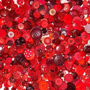 May include: A large collection of red buttons in various sizes and styles. The buttons are made of plastic and have a smooth, shiny finish.
