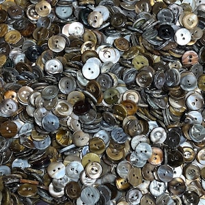 May include: A large collection of assorted buttons in various shades of brown, gray, and white. The buttons are made of a smooth, shiny material and have a variety of shapes and sizes.