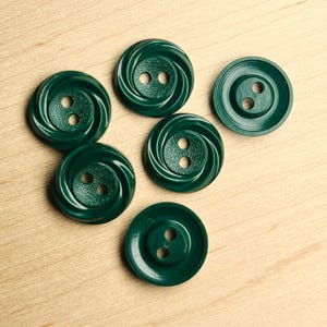 May include: Six dark green plastic buttons with two holes each. The buttons have a swirl design and a textured surface.