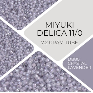 Puede incluir: Primer plano de un tubo de cuentas Miyuki Delica 11/0 en el color DB80 Crystal Lavender. El tubo contiene 7,2 gramos de cuentas.