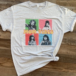 May include: A gray t-shirt with a colorful graphic of four women and the text "MOM VIBES" in yellow letters.