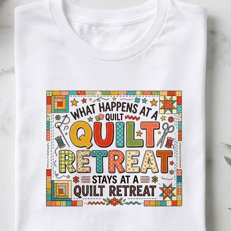 May include: White t-shirt with a colorful graphic that reads "WHAT HAPPENS AT A QUILT RETREAT STAYS AT A QUILT RETREAT." The design includes quilting-themed elements like scissors, spools of thread, and star shapes. The text is in various colors and fonts.
