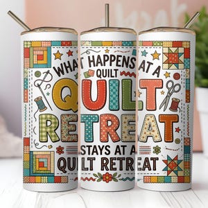 May include: A white tumbler with a straw, featuring a colorful patchwork design and the text "WHAT HAPPENS AT A QUILT RETREAT STAYS AT A QUILT RETREAT." The design includes stars, scissors, and spools of thread.